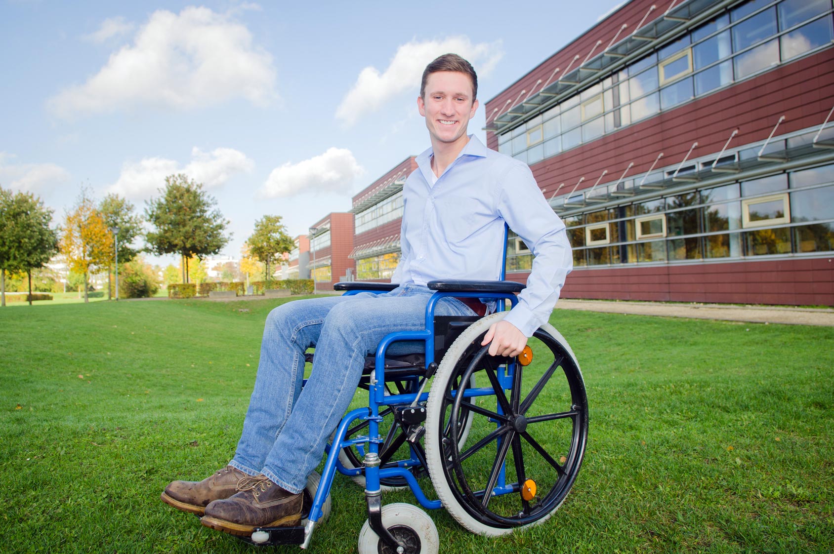 Auszubildender im Rollstuhl vor Schule