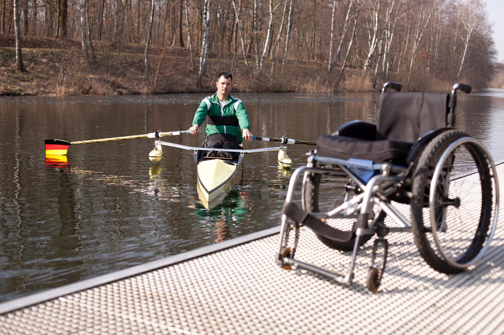 Mann beim Wassersport. Rollstuhl steht an Land.